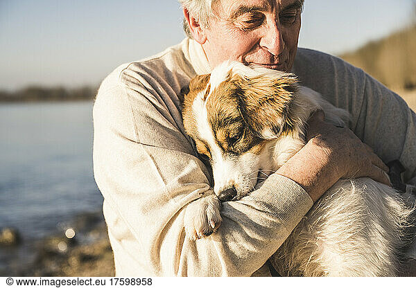 Senior man hugging dog on sunny day