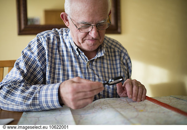 Senior man looking at a road map using magnifier