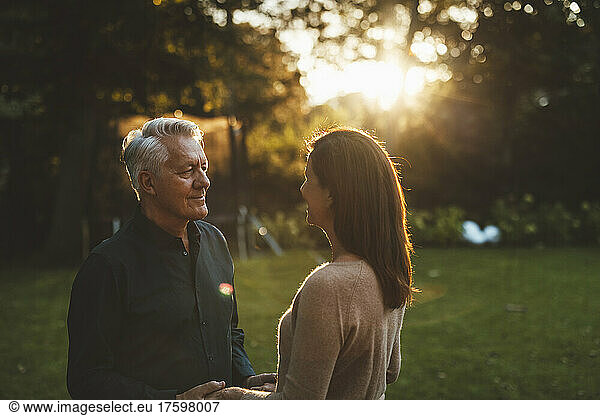 Senior man looking at woman in garden on sunset