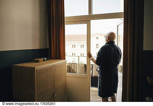 Senior man looking out while standing in doorway