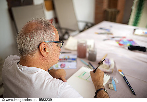 Senior man painting watercolor.