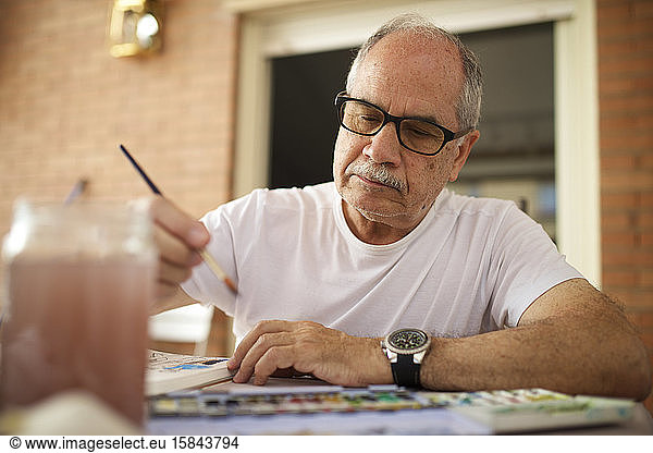 Senior man painting watercolor.