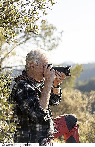Senior man photographing in nature