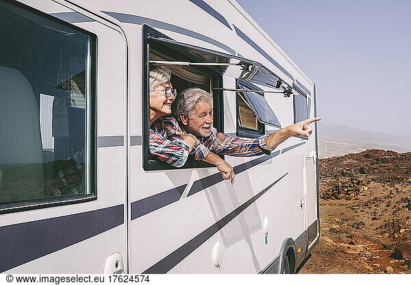 Senior man pointing by woman looking through window of camper van on sunny day
