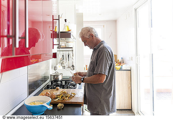 Senior man preparing potatoes in his kitchen