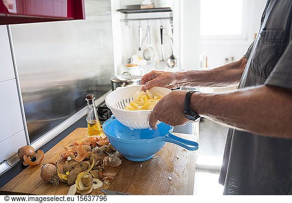 Senior man preparing potatoes in his kitchen