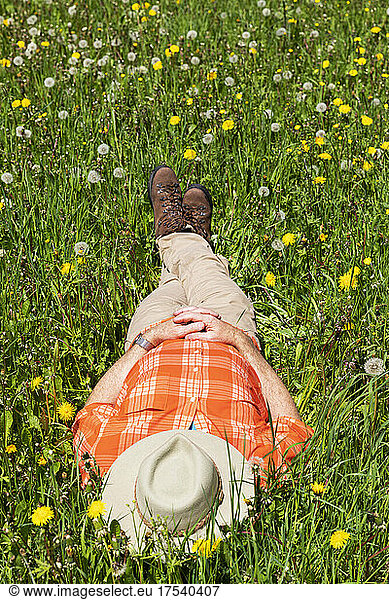 Senior man relaxing at meadow on sunny day