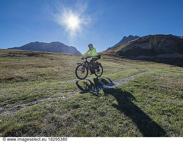 Senior man riding mountain bike on sunny day under blue sky  Vanoise National Park  France