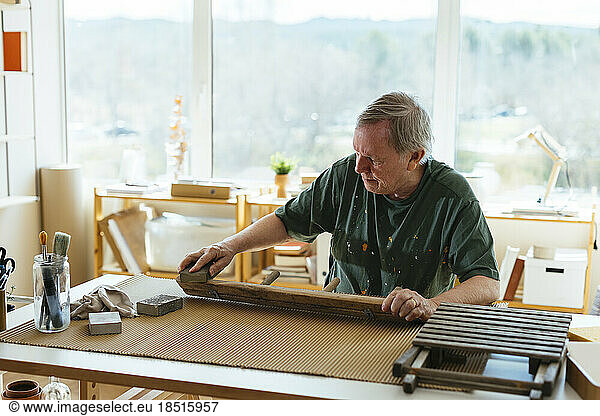 Senior man scarping wood in workshop