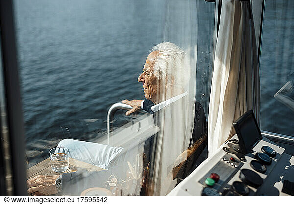 Senior man sitting at houseboat seen through windshield