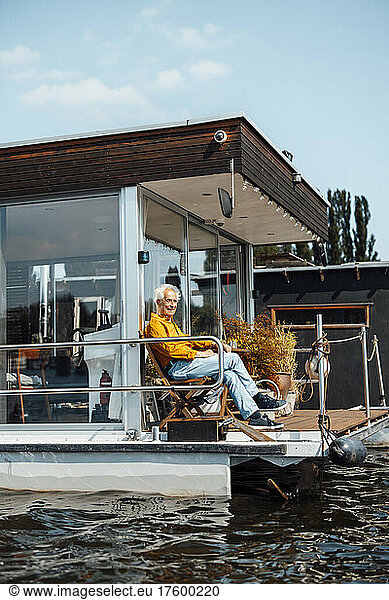 Senior man sitting on chair at houseboat