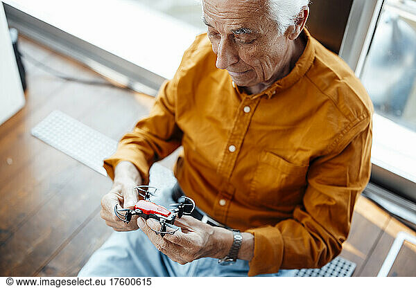 Senior man sitting with drone at houseboat