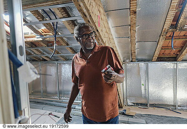 Senior man standing in attic at site