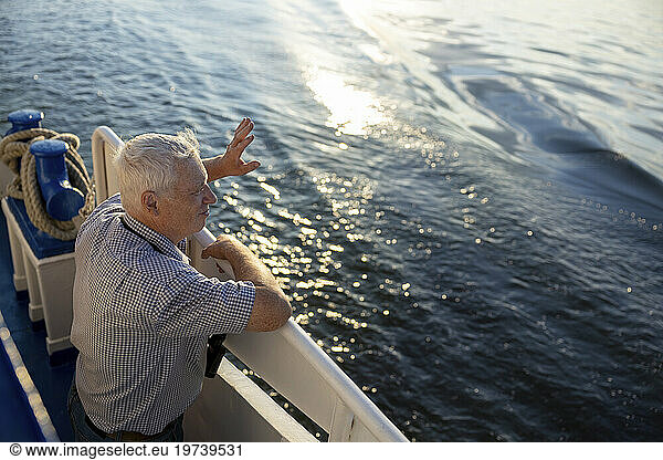 Senior man standing near railing and waving hand near sea