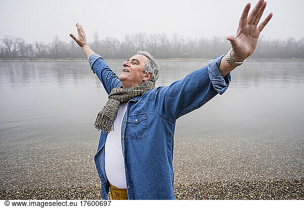Senior man standing with arms outstretched at beach