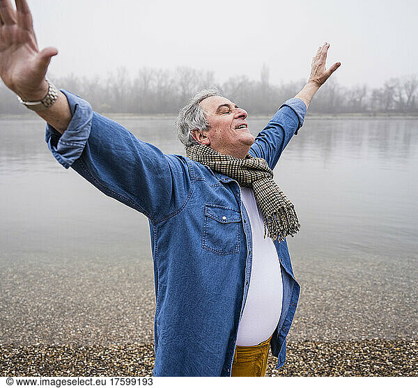 Senior man standing with eyes closed at beach