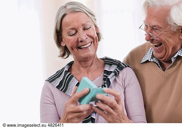 Senior man surprising woman with gift  smiling