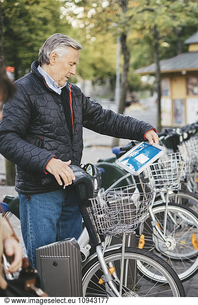 Senior man taking rental bike at parking lot