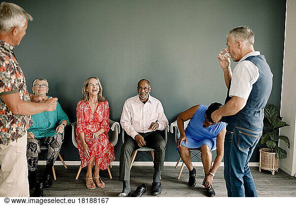 Senior man talking with happy male and female friends in dance class