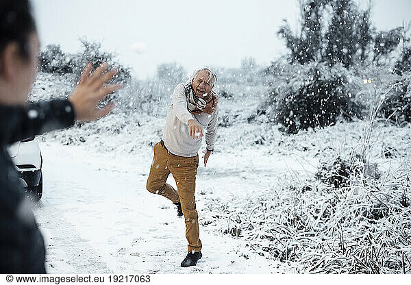Senior man throwing snowball at son