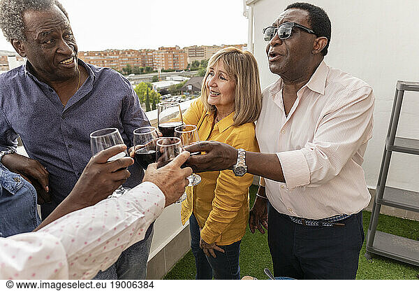 Senior man toasting wineglass with friends in balcony
