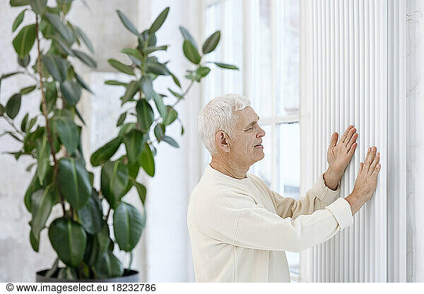 Senior man touching and examining radiator at home