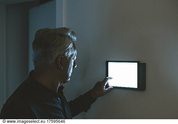 Senior man using smart home app on table PC at home
