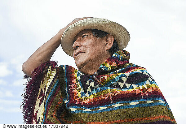 Senior man wearing poncho and hat while looking away