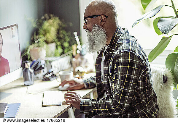Senior man with beard using computer in home office