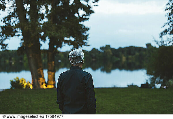Senior man with hair standing in garden at dusk