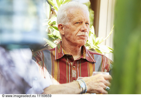 Senior man with moustache sitting outdoors.
