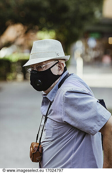 Senior man with protective face mask standing in park