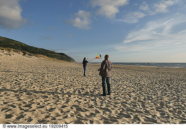 Senior man with woman flying kite at beach
