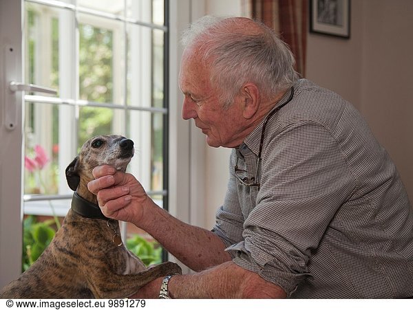 Senior Mann streichelt Haustier Hund