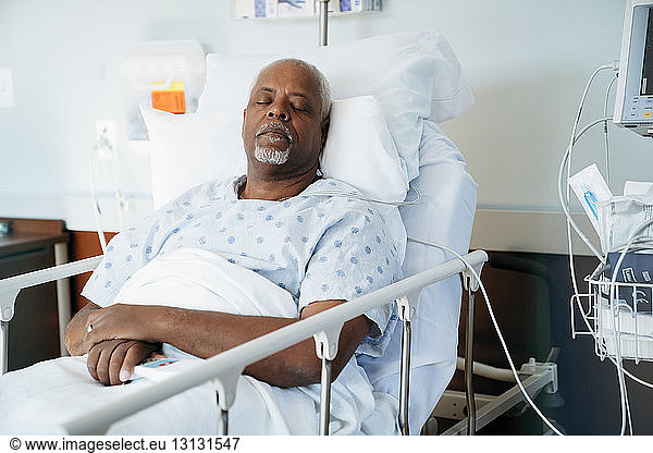 Senior patient sleeping on bed in hospital ward