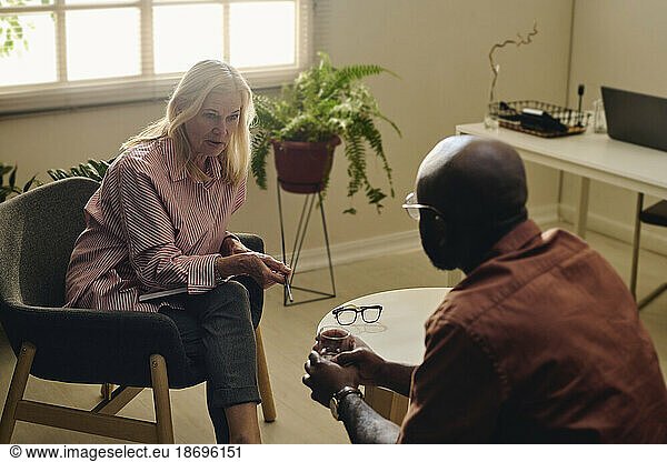 Senior psychologist consoling depressed patient at office