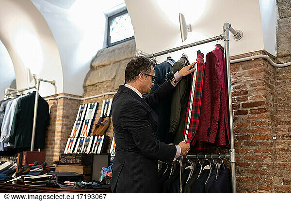 Senior tailor measuring sleeve of jacket
