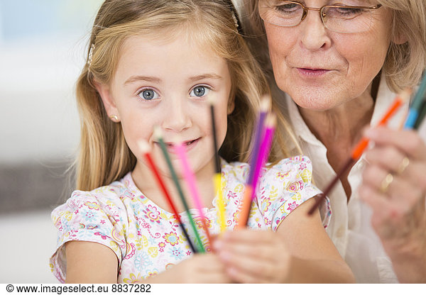 Senior woman and granddaughter showing coloured pencils