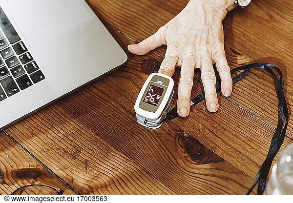 Senior woman checking pulse with oximeter at home