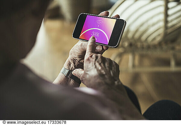 Senior woman checking wifi connection on smart phone at home