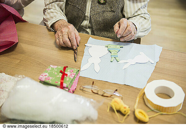 Senior woman cutting fabric in rabbit shape during Easter