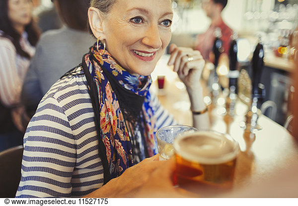 Senior woman drinking beer at bar