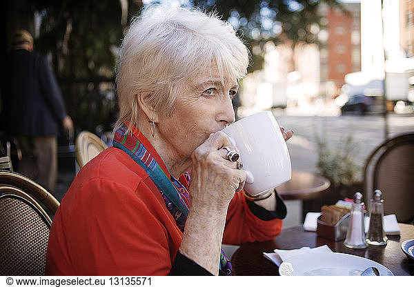 Senior woman drinking coffee at sidewalk cafe