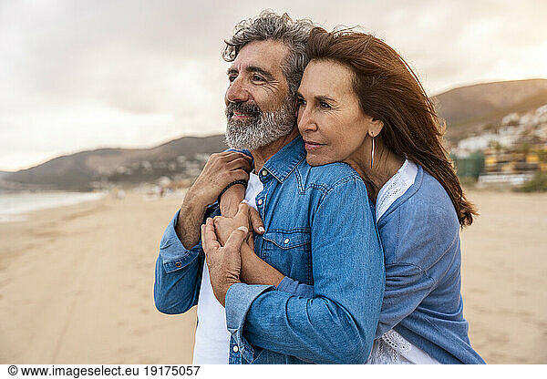 Senior woman embracing man at beach on weekend