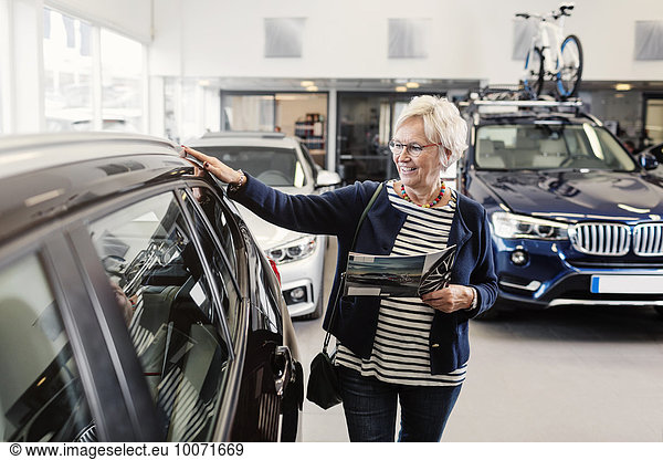 Senior woman examining car in store