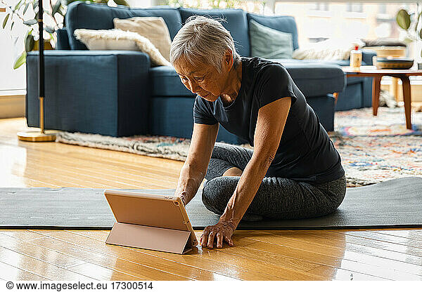 Senior woman exercising while learning through digital tablet