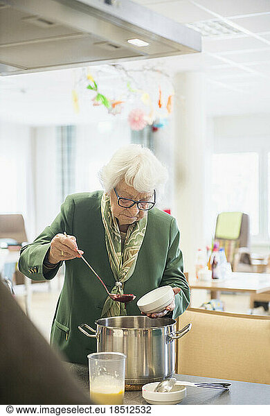 Senior woman filling and portioning the dessert in bowls at rest home