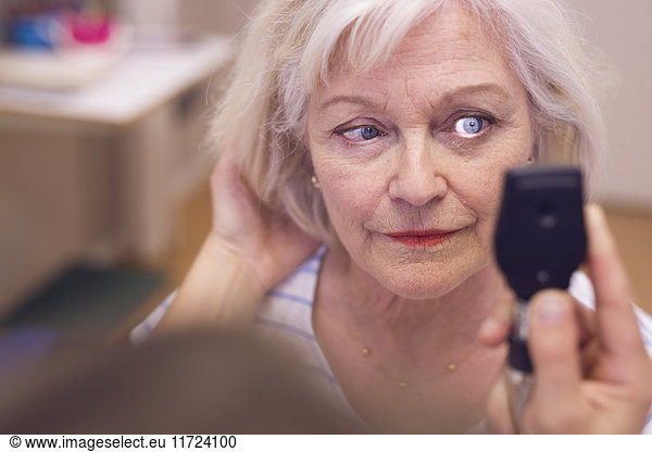 Senior woman having eyes checked by doctor