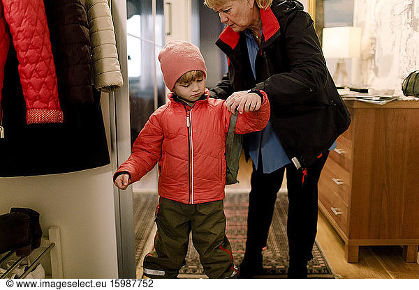 Senior woman helping grandson in wearing bag at home