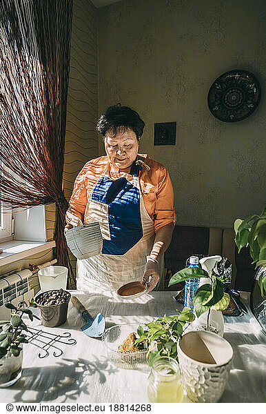 Senior woman holding flower pot preparing for planting